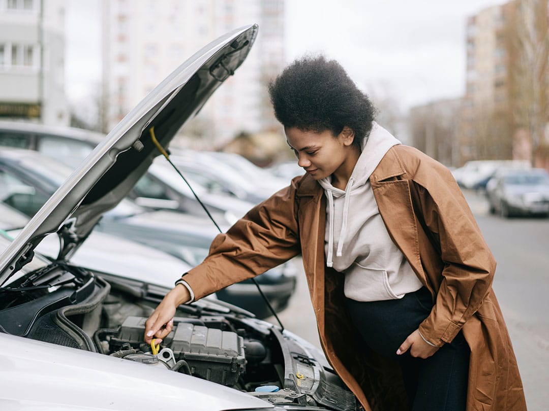 Woman checking car engine oil leve