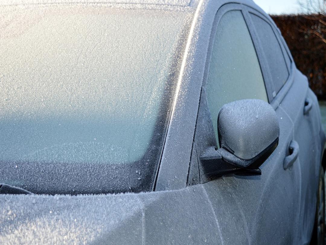 A car and its windscreen covered in ice